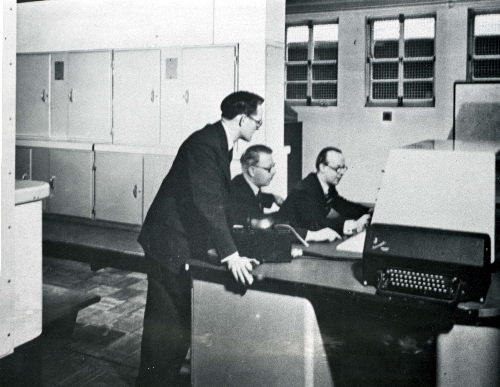 Computer pioneer Tom Kilburn (standing) and two colleagues at the Ferranti Mark I computer console